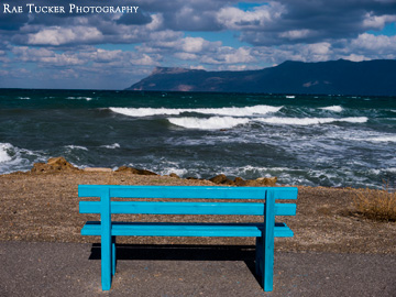 A blue bench provides a place to watch the waves roll in in Kissamos, Greece