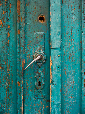 Turquoise paint peels and cracks on this wooden door in Brasov, Romania