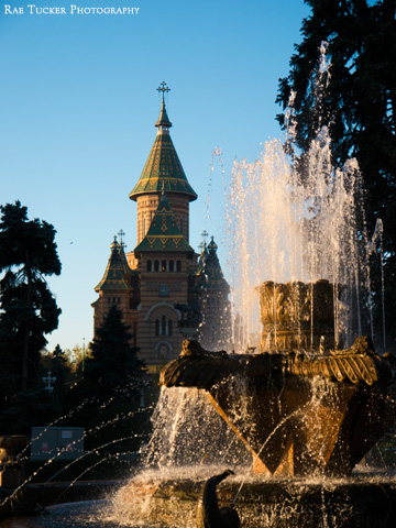 The morning sun illuminates a fountain that stands before the Orthodox cathedral in Timisoara, Romania