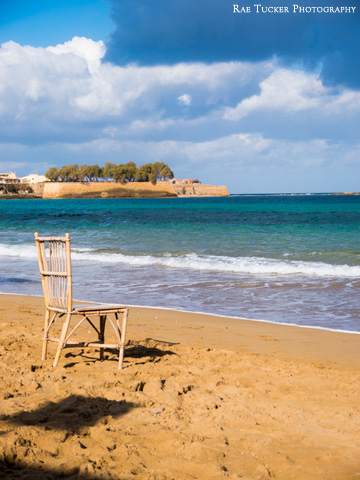 A chair on the beach overlooks the Aegean sea in Greece.