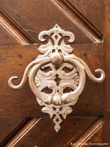 An ornate door knocker on a wooden door.