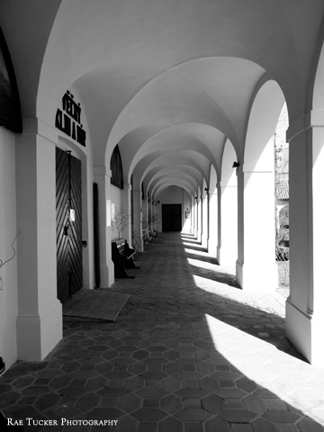 A black and white image of a walkway lining a church courtyard in the South Bohemia region of the Czech Republic.
