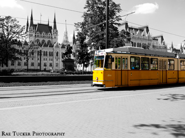 An old-fashioned, yellow tram against a black and white background in Budapest, Hungary