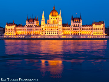 The Hungarian Parliament glows along the Danube river in the early evening in Budapest