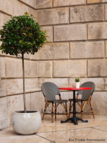 A table and chairs against a stone wall at the Opera Cafe in Budapest, Hungary