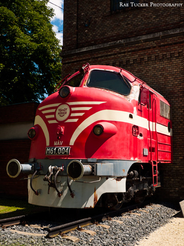 A red train appears to be emerging from a brick building in Tapolca, Hungary