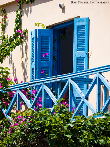 A blue balcony and shutters with pink flowers in Gavdos, Greece