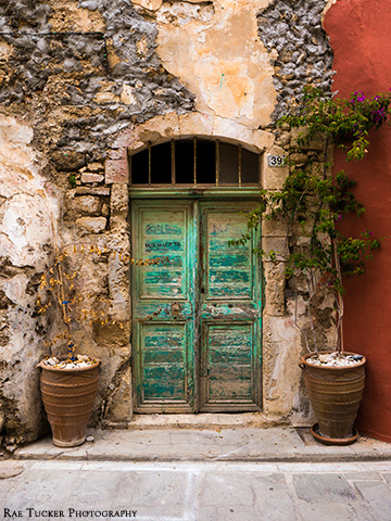 An old, turquois door on a weathered wall in Rethymno, Greece