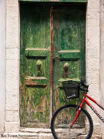 A wooden, green door with a bicycle in front