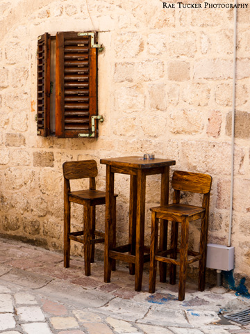 Wooden shutters and a wooden bar table and chairs on a stone street in Kotor, Montenengro