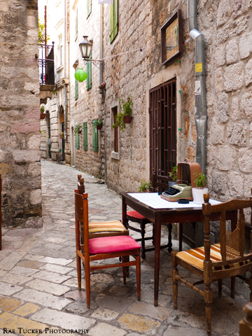 A wooden table, typewriter and other decorations adorn a small stone street in Kotor, Montenegro
