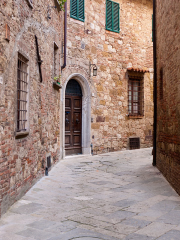 An old stone street bends around a corner in Montepulciano, Italy.