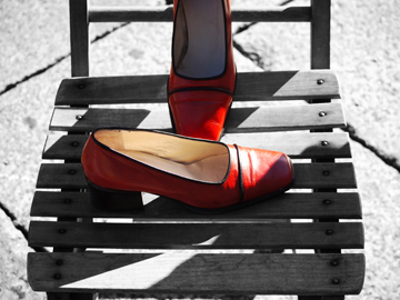 A pair of red shoes on a black and white, wooden chair