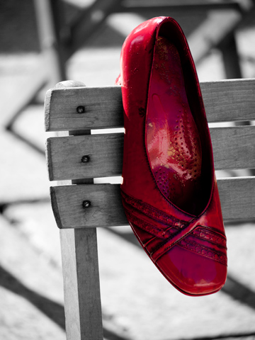 A red shoe on a wooden chair.