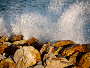 The spray of crashing waves on golden rocks.