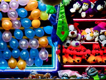 Carnival prizes displayed at a balloon popping game at a fair