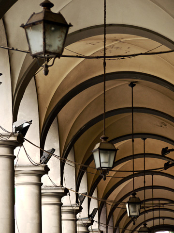 Lanterns hang down this arched walkway outside an apartment building in Florence, Italy
