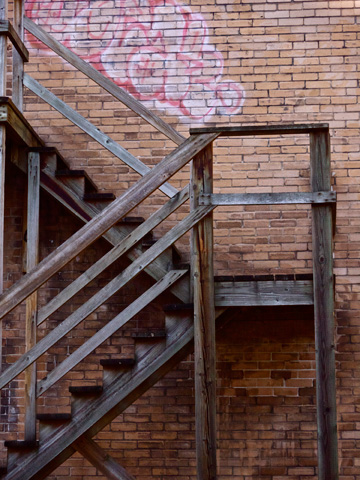 A wooden stairwell along a graffitti laden brick wall in Vancouver, British Columbia