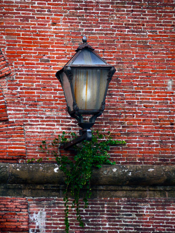 A lantern on a brick wall of the Fortezza in Florence, Italy