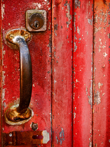 The rusted handle and lock on a red door