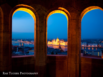 The Hungarian Parliament building, illuminated at night, as seen through the windows of Fisherman's Bastion in Budapest.