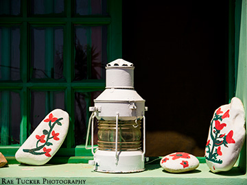 A lantern and painted rocks on a window ledge.