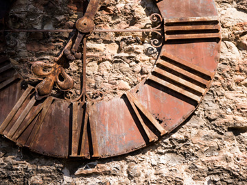 A rusted clocked on a stone wall