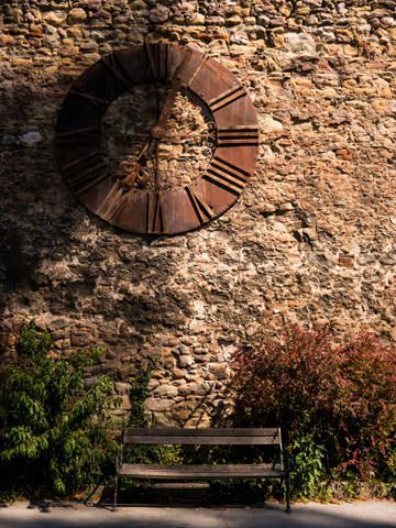 Late summer time passes on a bench under the large, rusted clock, whose hands are stopped at the time of a large earthquake in Zagreb, Croatia