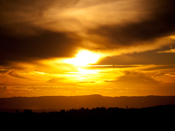 A sun sets over hills in Tuscany, Italy