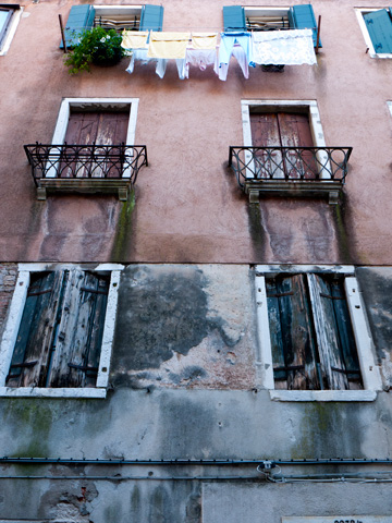 A wall of windows with wooden shutters in Venice, Italy.
