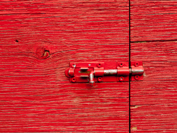 A red door held in place by a small latch