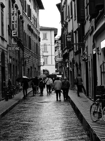 Pedestrians stroll under their umbrellas on the rainy streets of Florence
